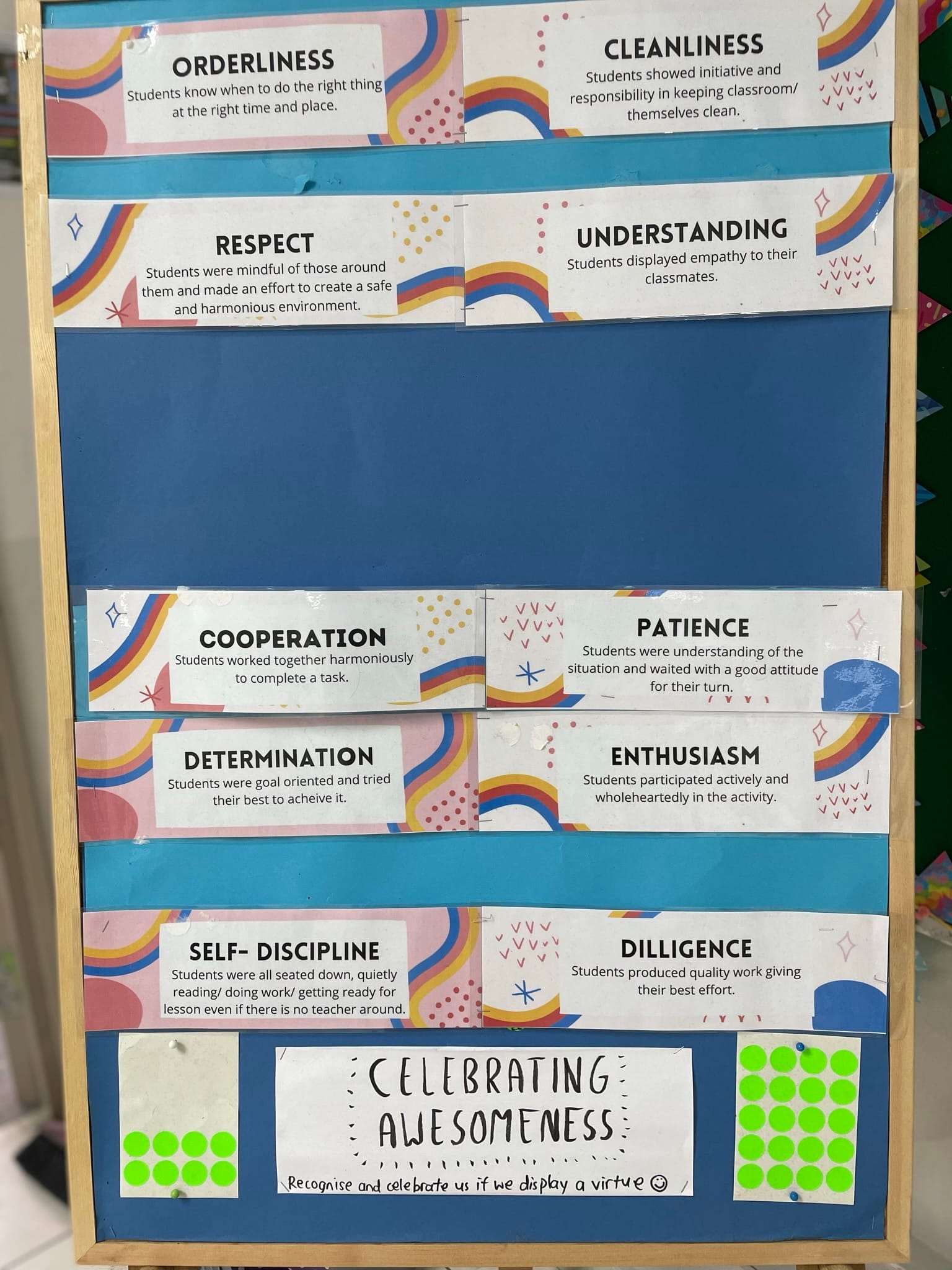 Classroom bulletin board listing student virtues like orderliness, respect, cooperation, and self-discipline with rainbow decorations.